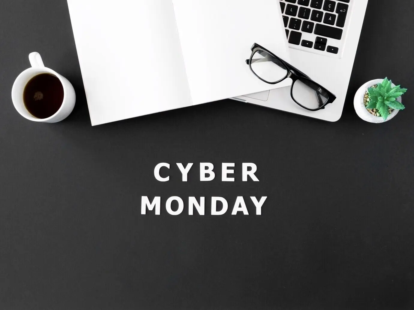 Overhead view of a laptop with coffee and glasses for Cyber Monday.